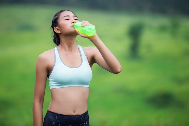 Asiatique jeune femme buvant de l&#39;eau après le coucher du soleil jogging