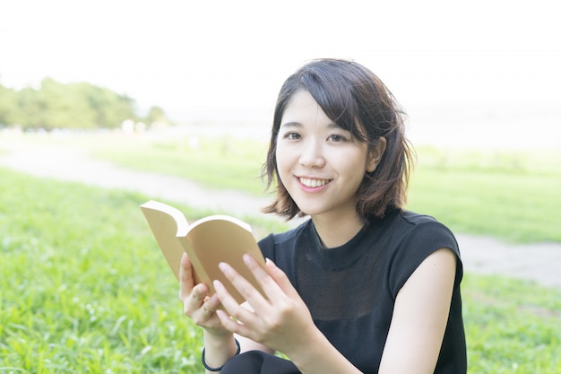 Asiatique jeune femme lisant un livre dans le parc