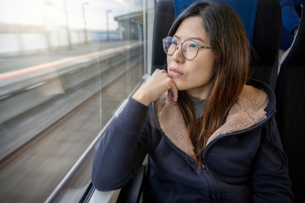 Asiatique jeune femme passagère Assis dans une humeur dépressive près de la fenêtre à l&#39;intérieur du train