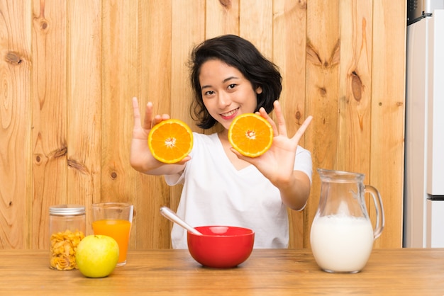 Asiatique jeune femme prenant son petit déjeuner en tenant une orange