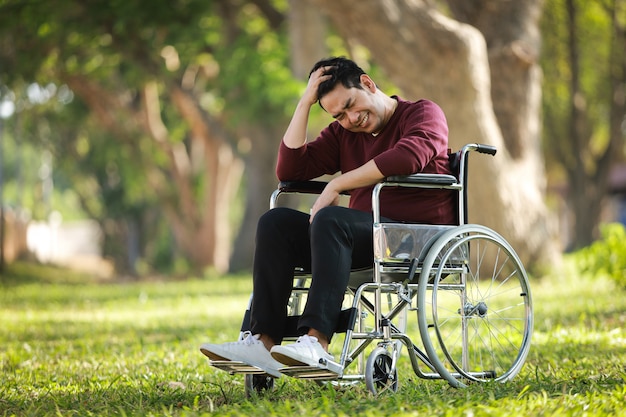 Asiatique jeune homme assis sur le fauteuil roulant à l'hôpital du parc