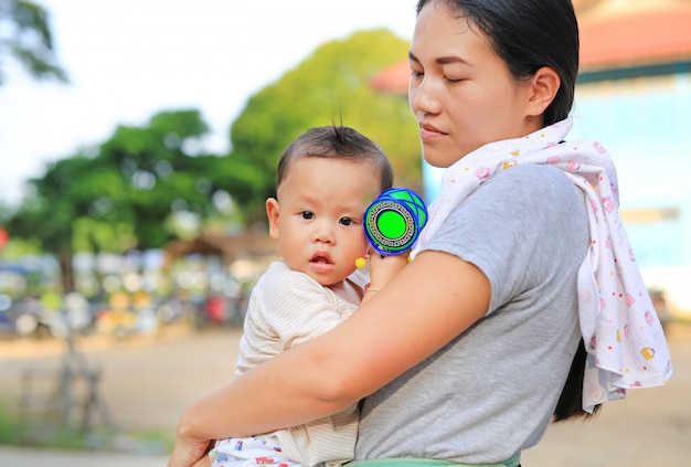 Asiatique mère portant son bébé bébé en plein air.