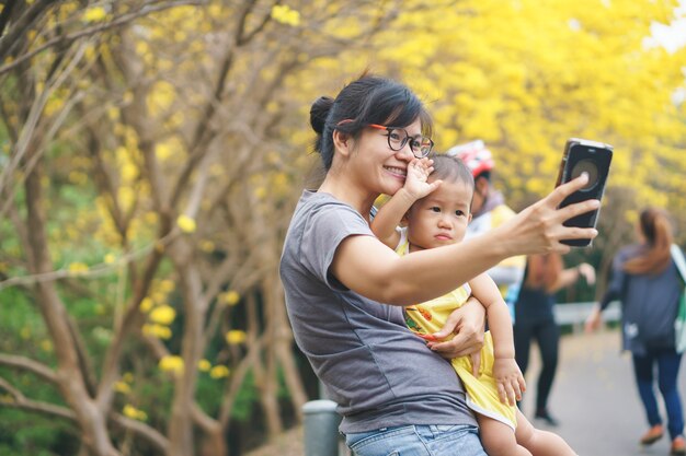 Asiatique mère et son fils dans le parc avec fleur de trompette jaune