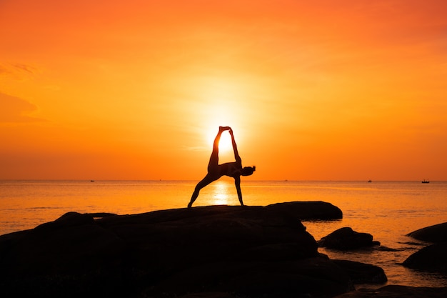 Asiatique pratiquant le yoga sur la plage au lever du soleil le matin