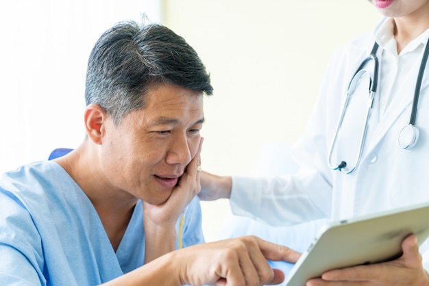 Asiatique senior patient sur un lit d&#39;hôpital discuter avec une femme médecin