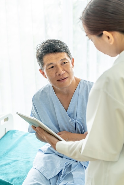 Asiatique senior patient sur un lit d&#39;hôpital discuter avec une femme médecin