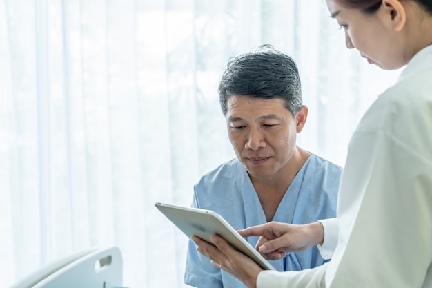 Asiatique senior patient sur un lit d'hôpital discuter avec une femme médecin