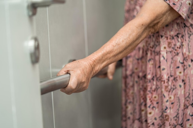 Asiatique senior ou vieille dame âgée femme patient utiliser toilettes salle de bain poignée sécurité dans l'hôpital de soins infirmiers sain concept médical fort