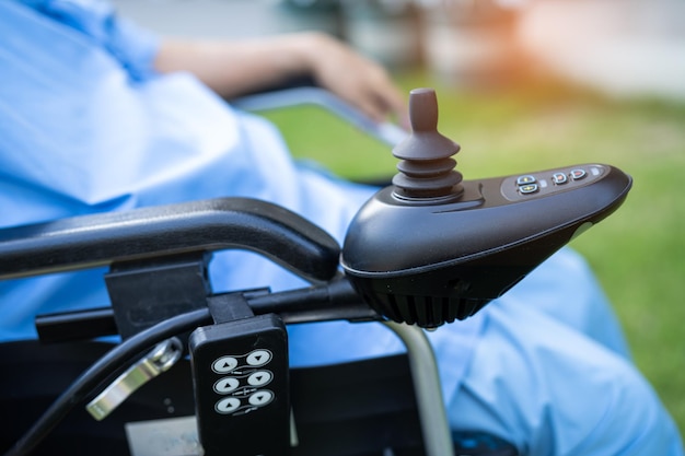 Asiatique senior ou vieille dame âgée patiente sur fauteuil roulant électrique avec télécommande à l'hôpital de soins infirmiers sain concept médical fort