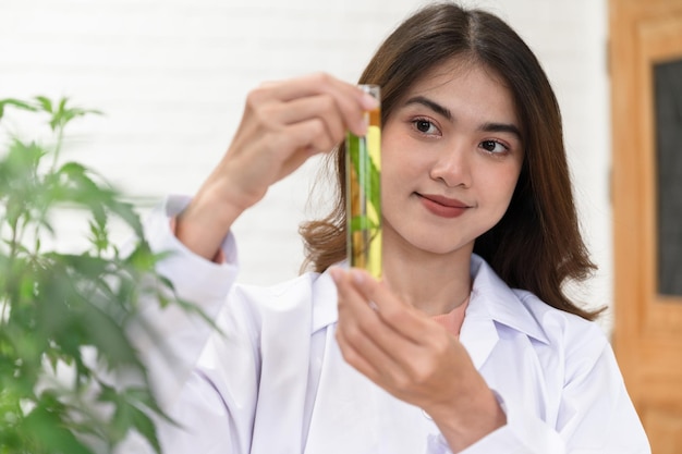 Asie Femme scientifique main tenant du cannabis dans un tube à essai sur les genoux