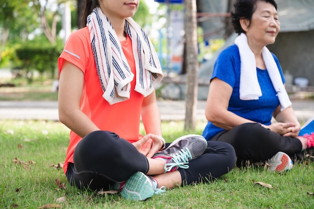 Asie senior et adolescente méditent au jardin