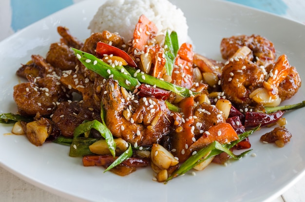 Asie et Sril Lanka goût - plat de riz et de crevettes à la pâte, sauce sucrée, décoré de graines de sésame sur une assiette blanche.