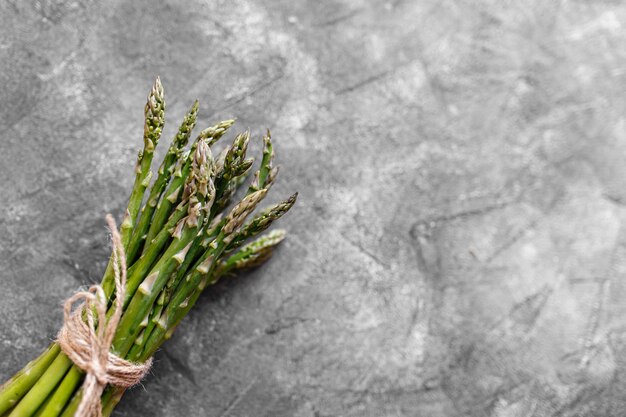 Asperges. Asperges vertes fraîches sur fond rustique gris. Espace de copie vue de dessus. Des bouquets d'asperges vertes