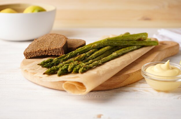 Asperges au four et pain noir sur un fond en bois.