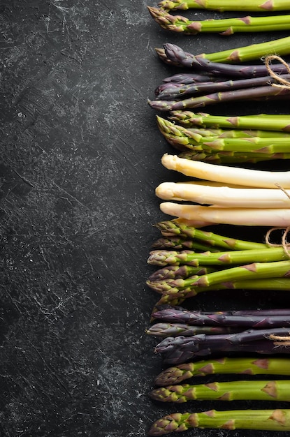 Asperges biologiques sur fond noir Ensemble d'asperges colorées Vue de dessus Espace libre pour votre texte