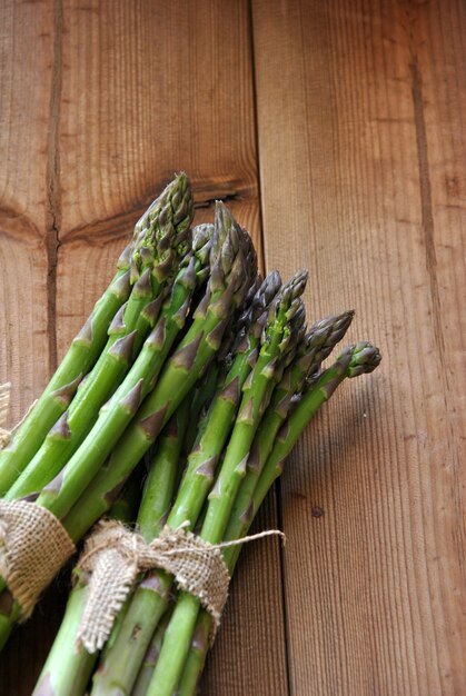 Asperges biologiques sur une table en bois accompagnée de tomates cerises et de laitue