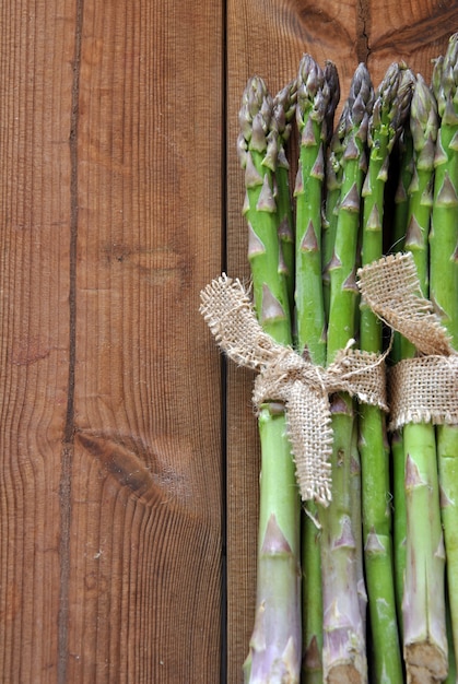 Asperges biologiques sur une table en bois accompagnée de tomates cerises et de laitue