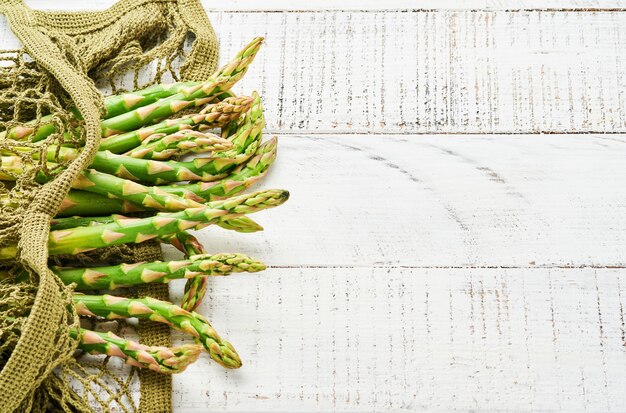 Asperges. Bouquet d'asperges vertes fraîches prêtes pour la cuisson sur fond de bois ancien blanc. Espace de copie vue de dessus.