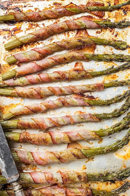 Asperges enveloppées de bacon sur un plateau de barbecue. Fond blanc. Vue de dessus.