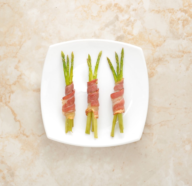 Asperges enveloppées dans du bacon sur une assiette