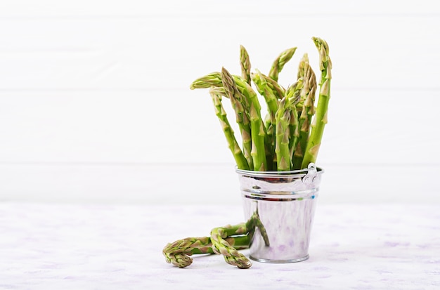 Asperges fraîches dans le seau sur fond clair.