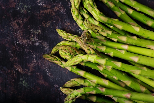 Asperges fraîches sur une surface sombre. Mise à plat. Vue de dessus