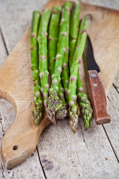 Asperges de jardin crus frais et couteau closeup sur une planche à découper