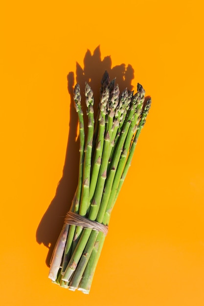 Asperges avec lumière dure à la mode et ombres fond orange