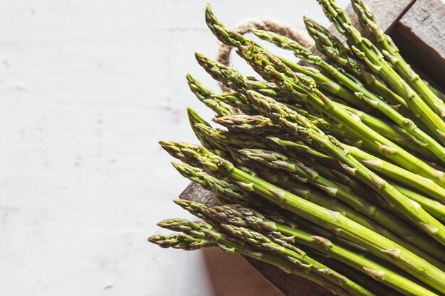 Asperges sur une planche à découper sur un vieux fond blanc