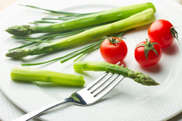 Asperges vertes aux tomates rouges sur plaque blanche