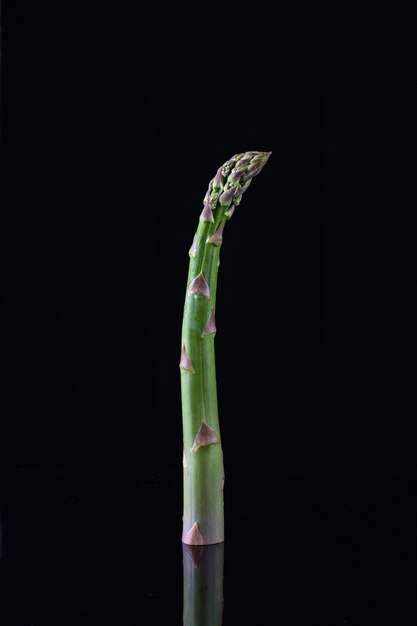 Asperges vertes biologiques fraîches isolées sur mur noir. photo en gros plan