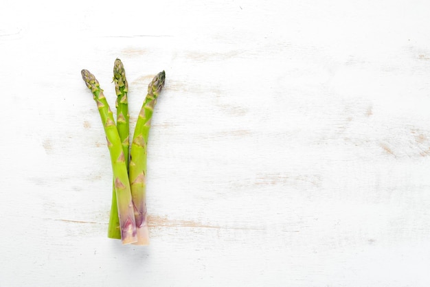 Asperges vertes fraîches sur un fond en bois blanc Alimentation saine Vue de dessus Espace libre pour votre texte