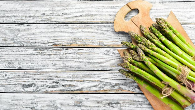 Asperges vertes fraîches sur un fond en bois blanc Alimentation saine Vue de dessus Espace libre pour votre texte