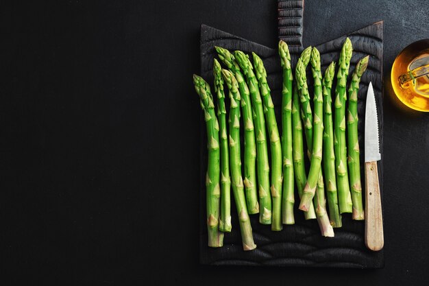 Asperges vertes sur une surface sombre prêtes pour la cuisson