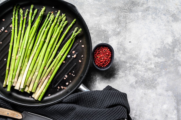 Asperges vertes vertes fraîches dans une casserole. Fond noir.