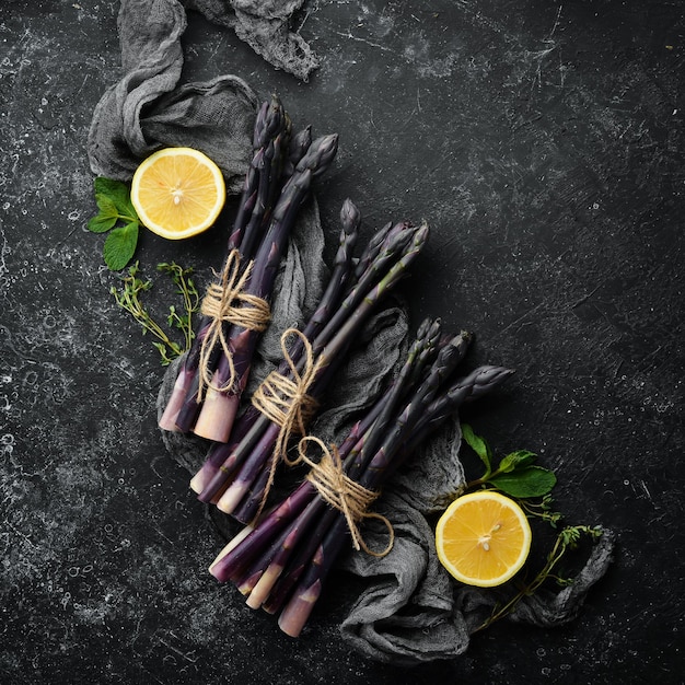 Asperges violettes fraîches au citron sur fond de pierre noire Alimentation saine Vue de dessus espace de copie gratuit