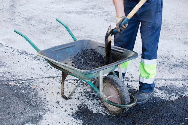 l'asphalte dans la brouette l'opérateur prépare le mélange avec l'uniforme