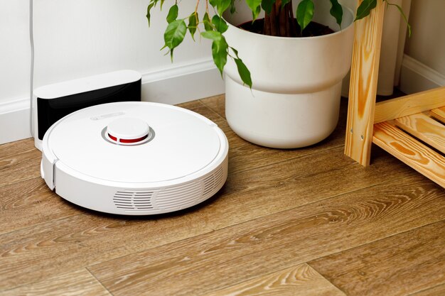 Aspirateur robot blanc sur plancher en bois