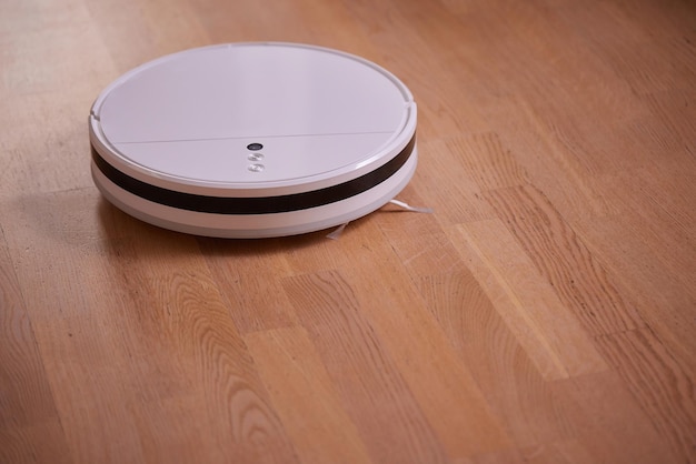 Aspirateur robot moderne sur parquet dans la chambre