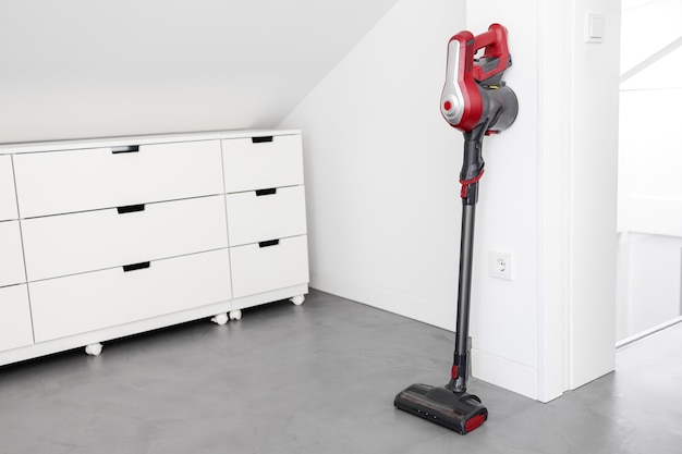 Aspirateur sans fil moderne appuyé sur un mur d'une pièce. Notion de devoirs