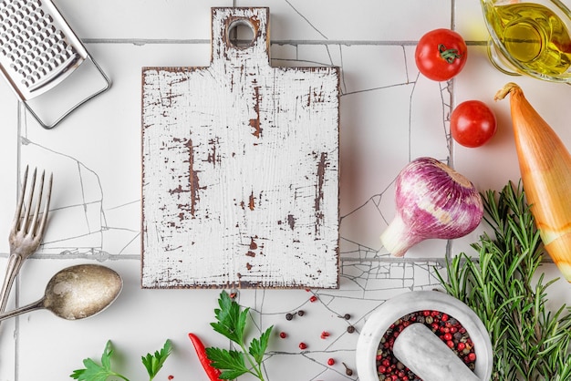 Assaisonnement épices herbes légumes planche à découper et ustensile de cuisine pour la cuisson des aliments vinaigrette sur table en carreaux blancs