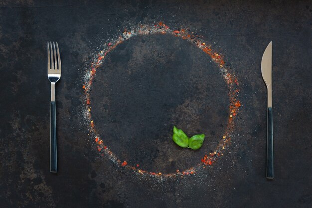 Assaisonnements sur la table, versés dans une assiette ronde et des couverts.