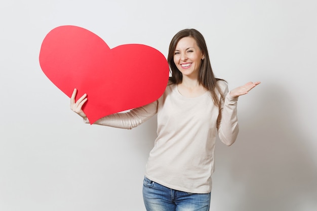 Assez amusante jeune femme souriante tenant un grand coeur rouge dans les mains isolés sur fond blanc. Copiez l'espace pour la publicité. Avec place pour le texte. Concept de la Saint-Valentin ou de la Journée internationale de la femme.