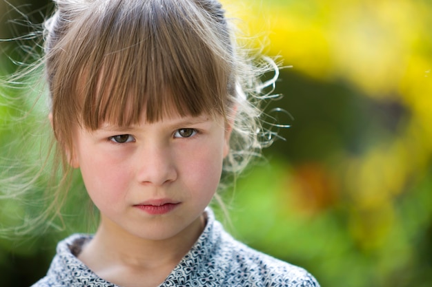 Assez drôle de mauvaise humeur jeune enfant fille en plein air se sentir en colère et insatisfait sur le concept de colère des enfants vert été floue.