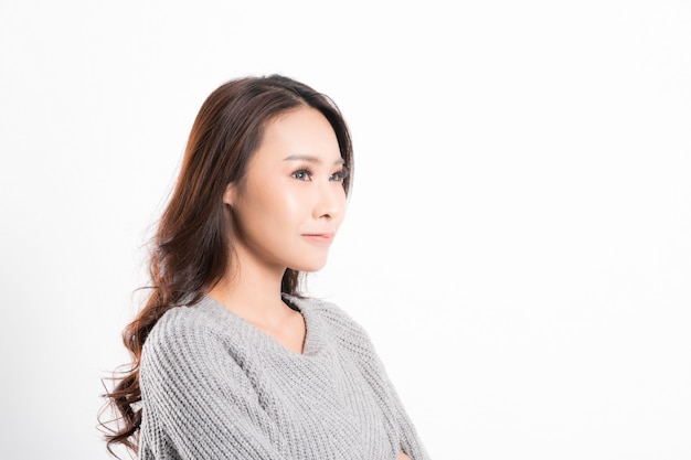 Assez souriant joyeusement étant heureux portrait de femme asiatique avec une peau parfaite et portant un pull gris de profil au studio tourné isolé sur fond blanc.