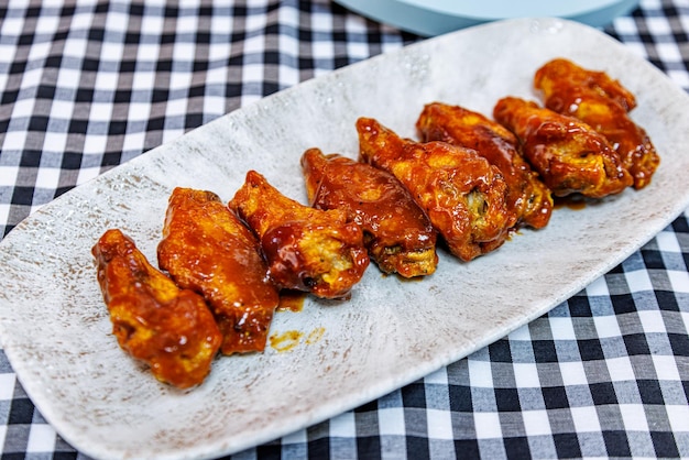 Photo assiette d'ailes de poulet grillées sur une nappe à carreaux noir et blanc