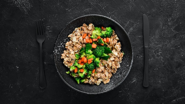 Une assiette d'aliments sains Farine d'avoine avec carottes brocoli et persil Vue de dessus Sur fond noir Espace de copie gratuit