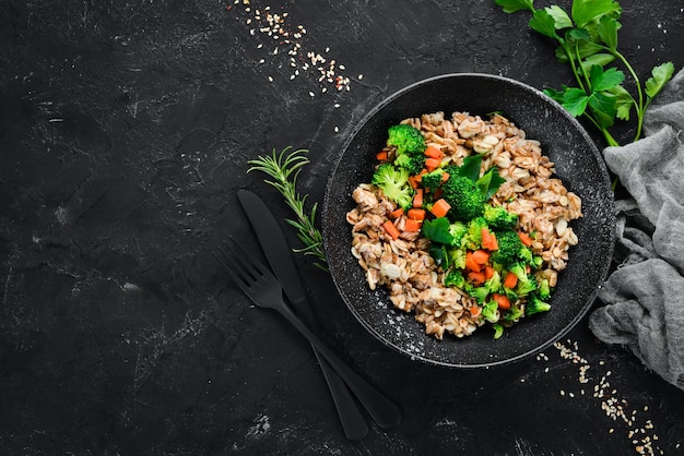 Une assiette d'aliments sains Farine d'avoine avec carottes brocoli et persil Vue de dessus Sur fond noir Espace de copie gratuit