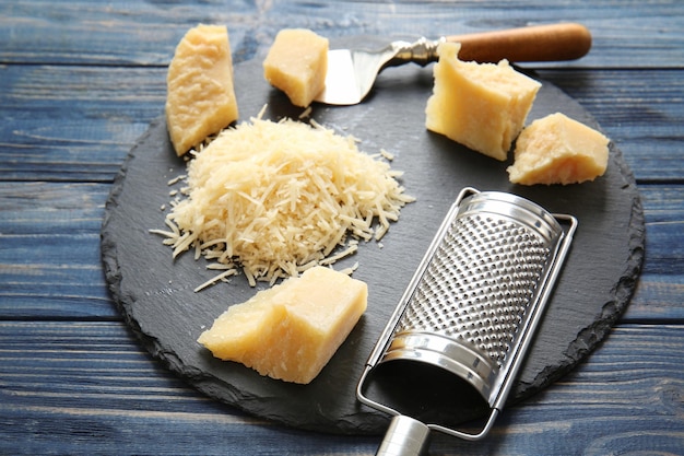 Assiette en ardoise avec fromage et râpe sur fond de bois