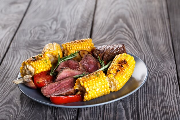 Assiette en argile bleue avec des tranches de steak et de maïs légèrement frits